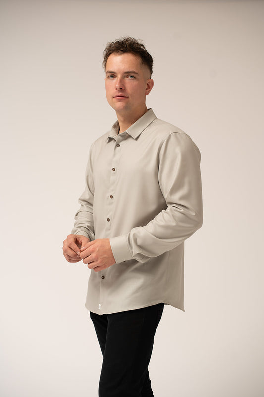 Man wearing a light gray button-up shirt against a plain background